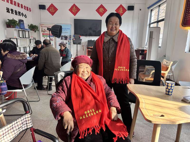 鹿邑智慧居家养老服务运营指挥中心内，老人佩戴'银龄管家社区养老服务驿站'红围巾合影。