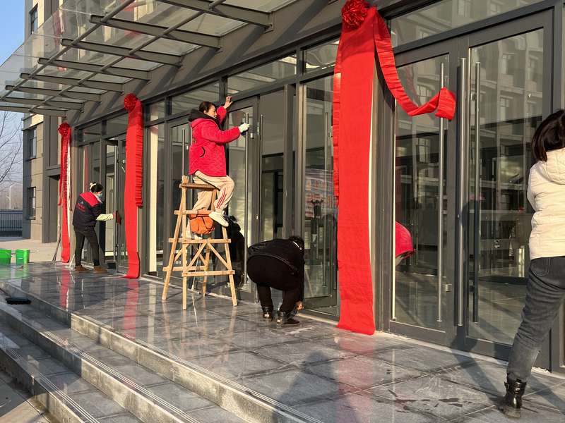 鹿邑某新建成办公楼交付前开荒保洁,工人擦拭玻璃门、台阶及入口区域。