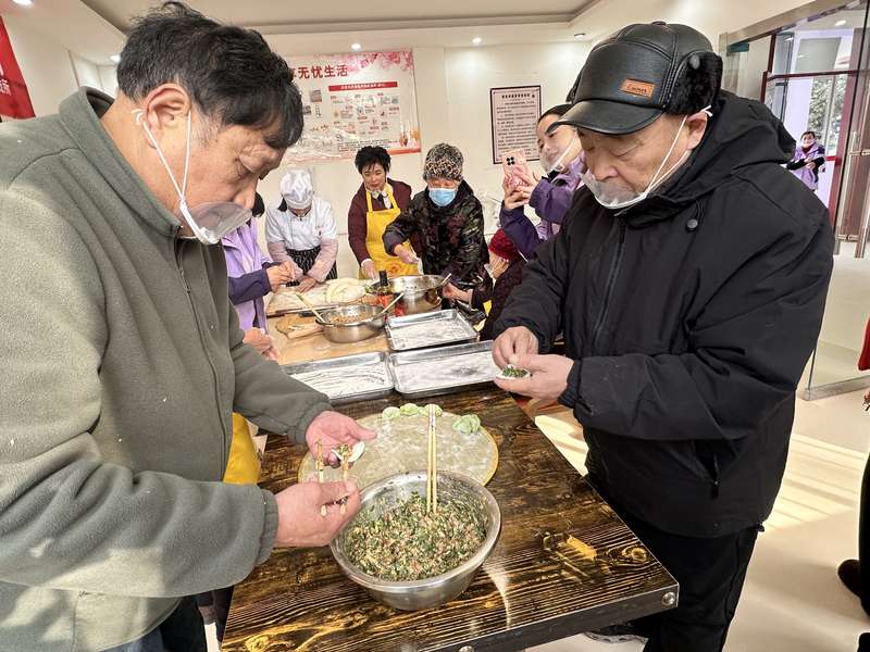 鹿邑社区老人在日间照料中心参与包饺子，体现助餐+社交相结合的社区养老服务。