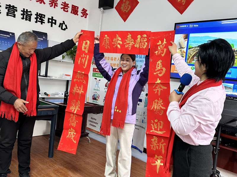 鹿邑智慧居家养老服务运营指挥中心春节活动,护理员与老人展示春联,营造节日氛围。